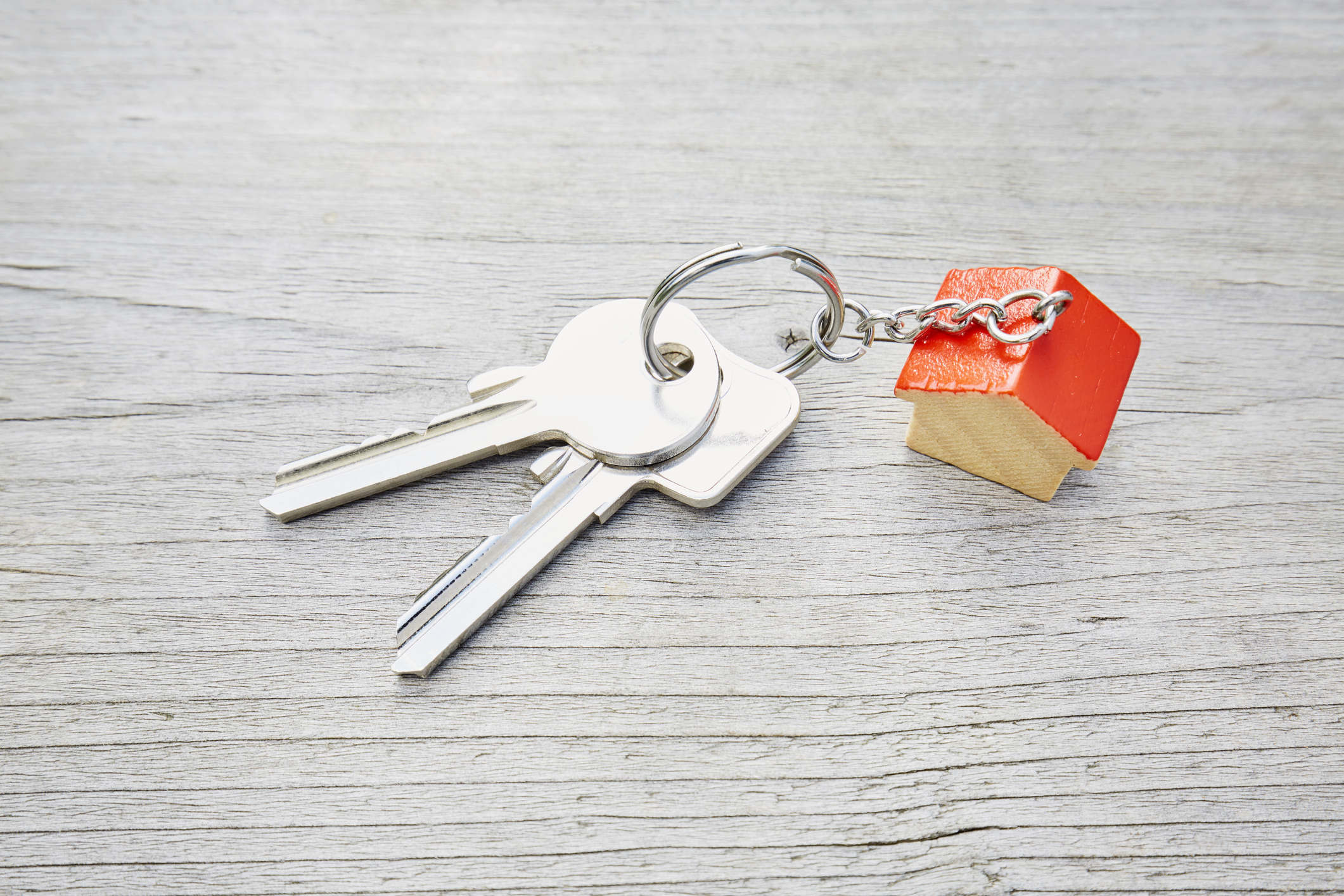 High angle view of keyring with a small red house and keys on wooden background