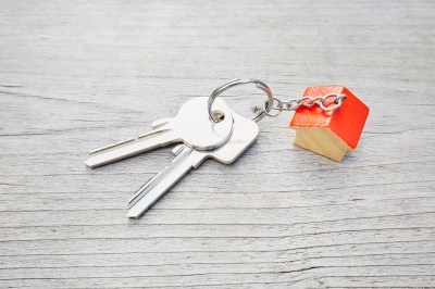 High angle view of keyring with a small red house and keys on wooden background