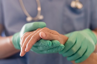 A physician holds the hand of a patient.
