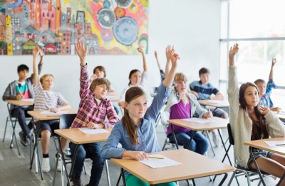 Students with arms raised in classroom