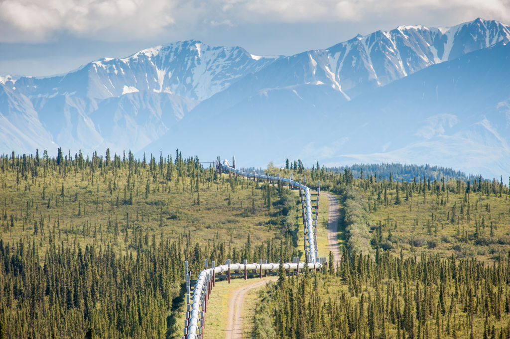 Trans-Alaska Pipeline (Alyeska pipleline) running through landscape with Mountain range in the distance in Alaska.