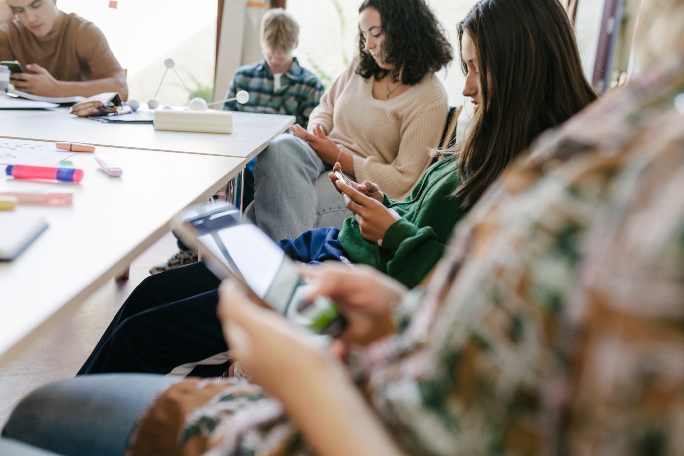 A group of high school students looking at their smartphones while taking a short break during class. (Via Getty Images)