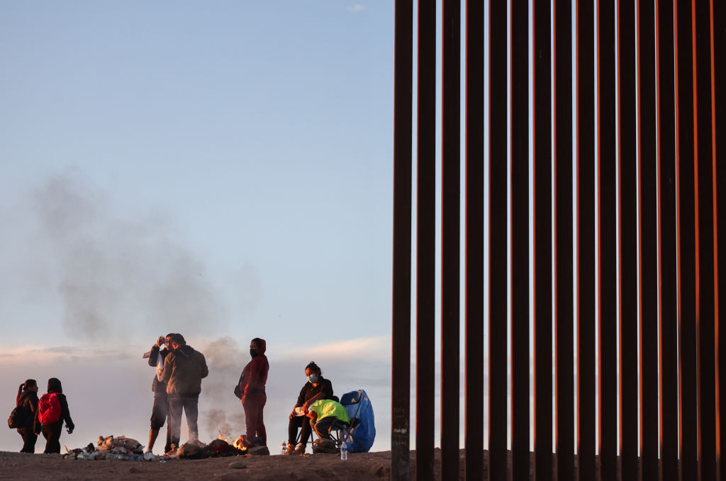 Migrants from Ecuador warm themselves by a fire along a gap in the U.S.-Mexico border. (Photo by Mario Tama/Getty Images)