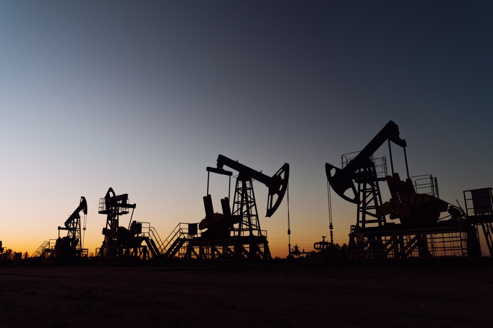 The silhouette of oil pumps on a sunset sky with sun setting. Environmental issue, pollution and damage, ecological risks. Siberia.
