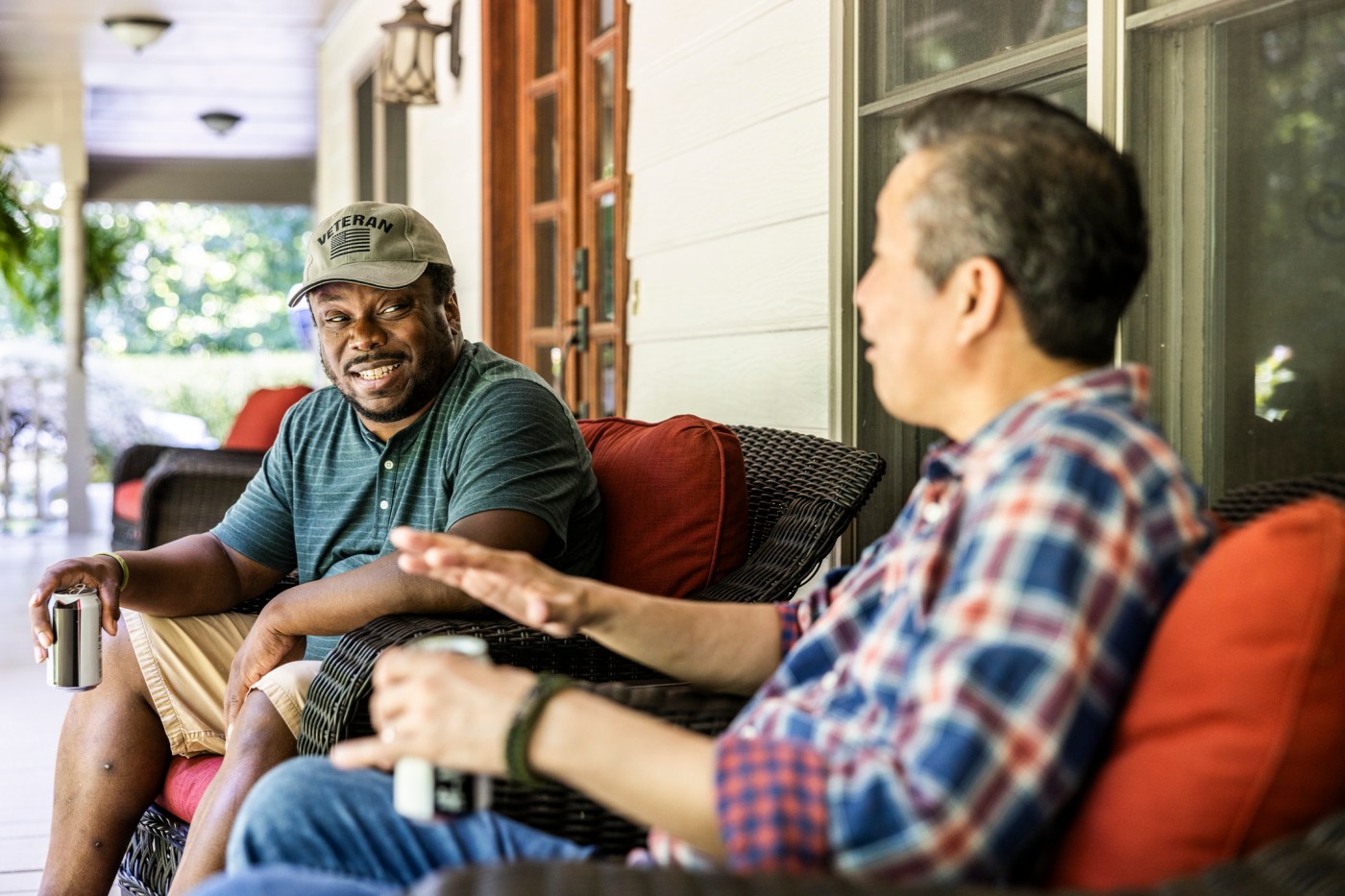 Senior U.S. military veterans laughing and talking on front porch of suburban home