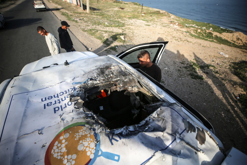 Palestinians stand next to a vehicle on April 2, 2024, in Deir al-Balah,  where humanitarian workers from the World Central Kitchen (WCK) were killed in an Israeli airstrike. (Photo by Majdi Fathi/NurPhoto via Getty Images)