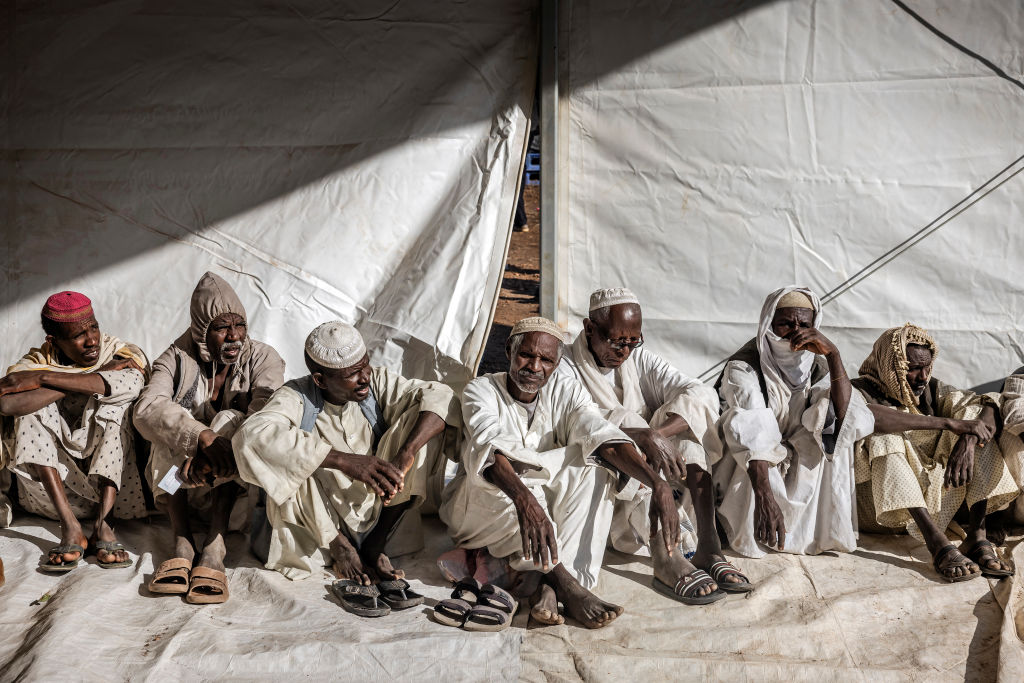 Sudanese men who have fled from the war in their country line up on February 15, 2024, during a cash assistance program at a Transit Centre for refugees in Renk, South Sudan. (Photo by LUIS TATO/AFP via Getty Images)