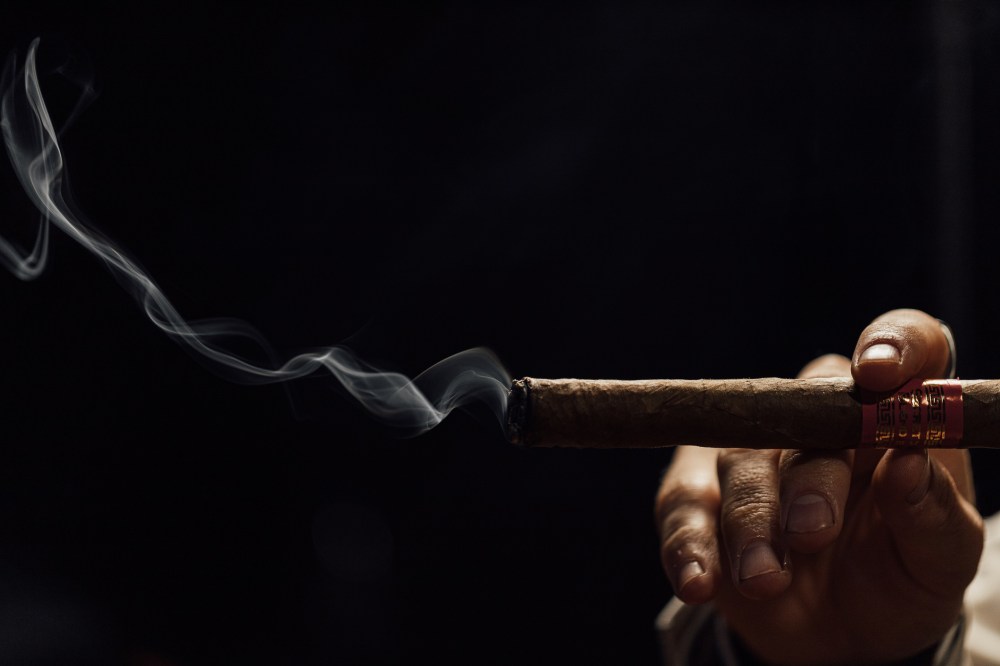 Man smoking cigar with smoke on a black background
