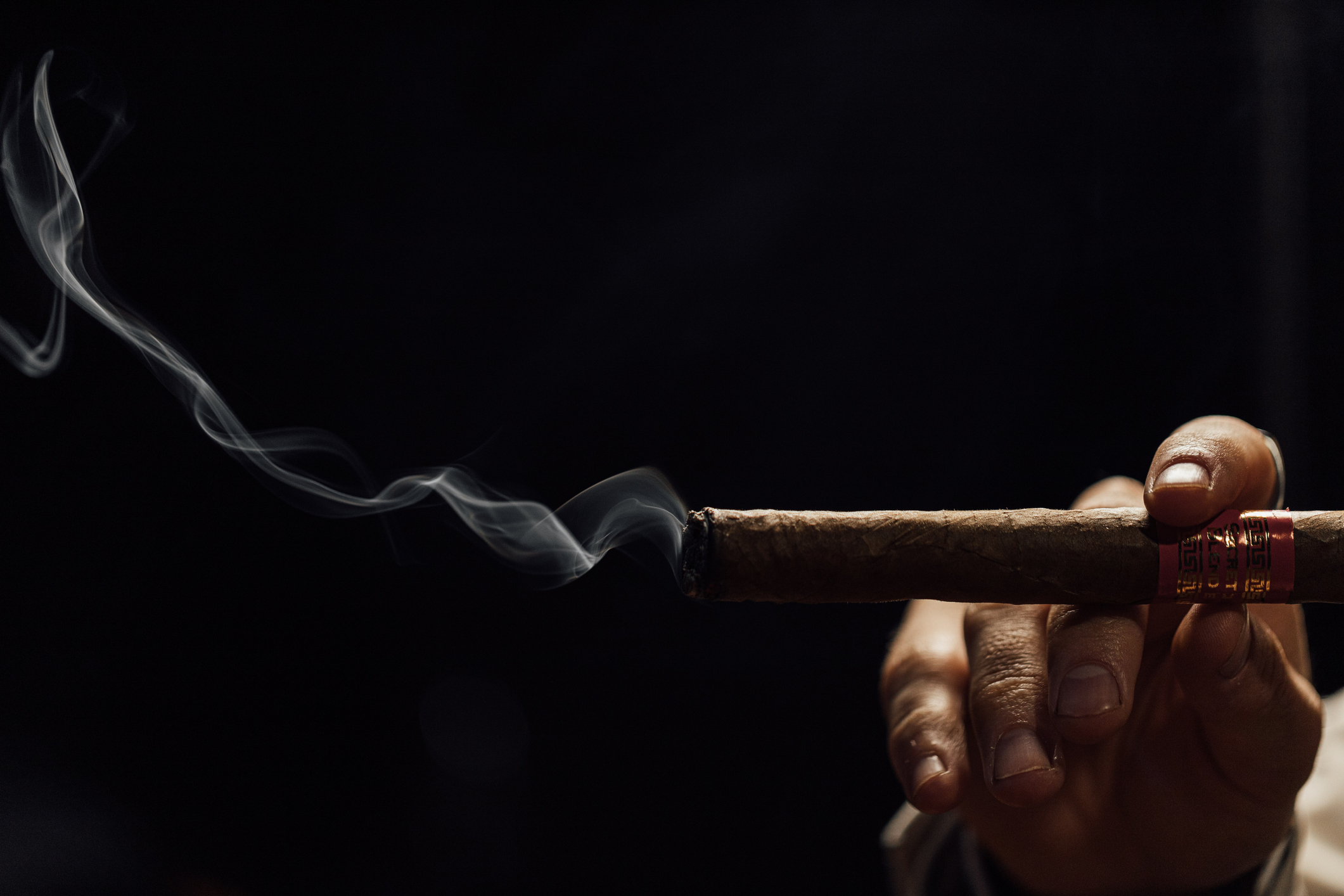 Man smoking cigar with smoke on a black background