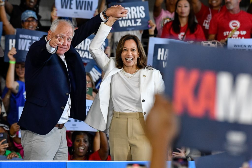 Minnesota Gov. Tim Walz raises the hand of Vice President Kamala Harris as she takes the stage to speak to several thousand attendees at a rally at Detroit Metropolitan Wayne County Airport in Romulus, Michigan, on August 7, 2024. (Photo by Adam J. Dewey/Anadolu via Getty Images)