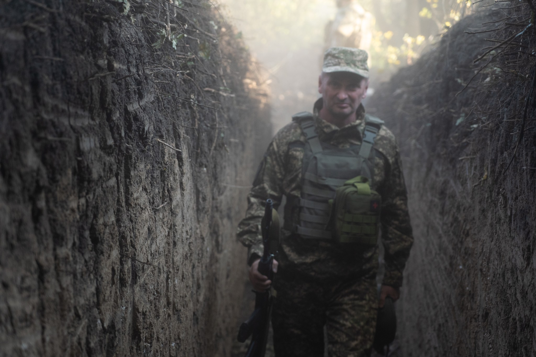 Dmytro walking in a trench, surrounded by dust after the cannon was fired. (Photograph by Joseph Roche)