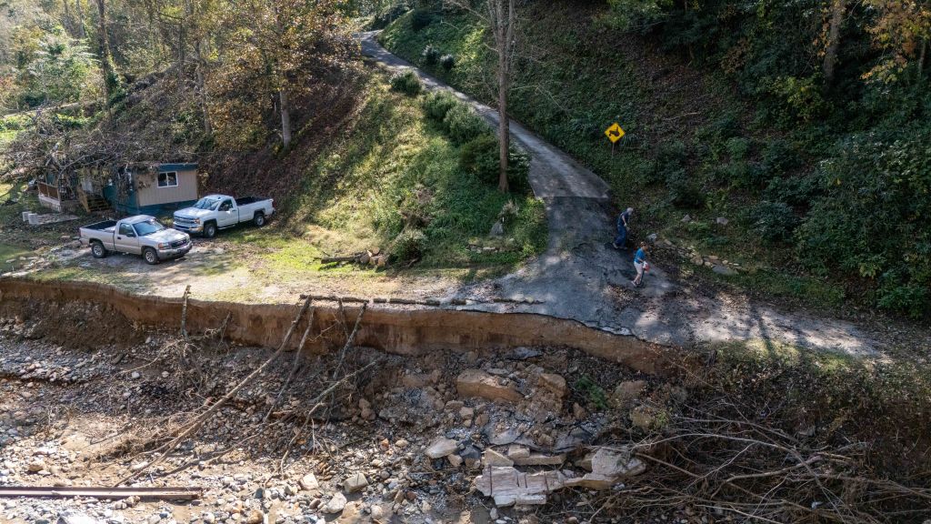 Residents near Armstrong Creek RV Park attend to yard cleanup in their driveway next to a washed-out bridge that had connected them to Highway 226A after flooding from Hurricane Helene on October 6, 2024, in Marion, North Carolina. (Photo by Steve Exum/Getty Images)