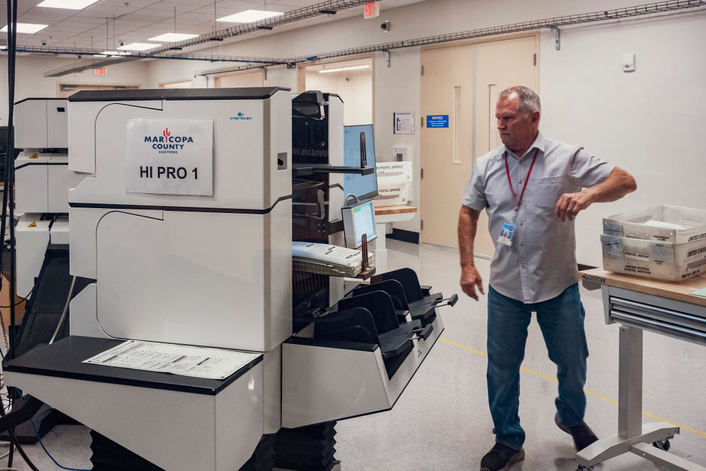 An election worker processes a stack of 2024 general election ballots with the tabulation machine at the Maricopa County Tabulation and Election Center in Phoenix on October 23, 2024. (Photo by Olivier Touron/AFP/Getty Images)