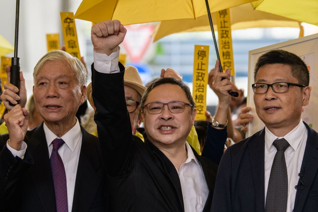 Baptist minister Chu Yiu-ming, law professor Benny Tai, and sociology professor Chan Kin-man, shout slogans with supporters before entering the West Kowloon Magistrates Court in Hong Kong on November 19, 2018. (Photo by ANTHONY WALLACE/AFP via Getty Images)