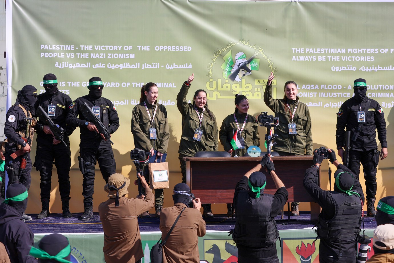 Hamas fighters escort four Israeli hostages, Naama Levy, Liri Albag, Daniella Gilboa and Karina Ariev, on a stage before handing them over to a team from the Red Cross in Gaza City on January 25, 2025. (Photo by Omar AL-Qattaa/AFP/Getty Images)