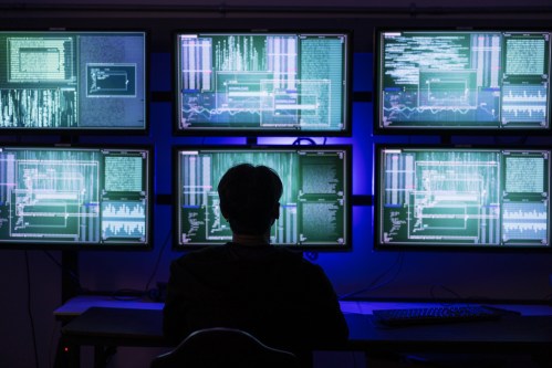 Dark Web Intrigue: Hacker Wearing Mask Explores Server Room – Cybersecurity in the Age of Information