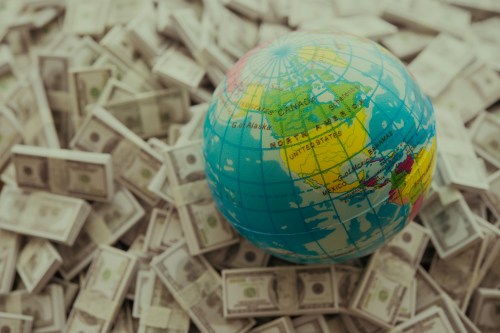 Focus on United states on world globe with US dollar bill banknotes pile background.