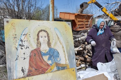 Elderly woman is seeing next to a portrait of Christ as she
