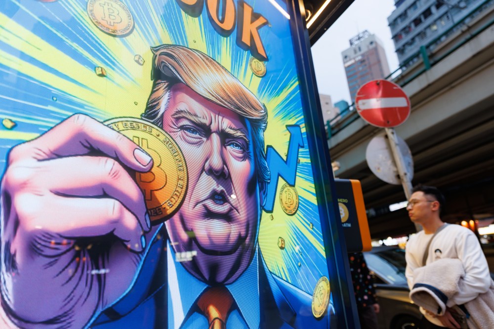 People walk past an advertisement feature Donald Trump with