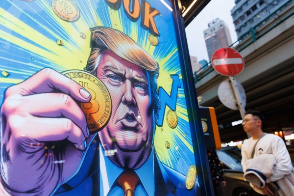 People walk past an advertisement featuring Donald Trump with Bitcoin in Hong Kong. (Photo by May James/SOPA Images/LightRocket/Getty Images)