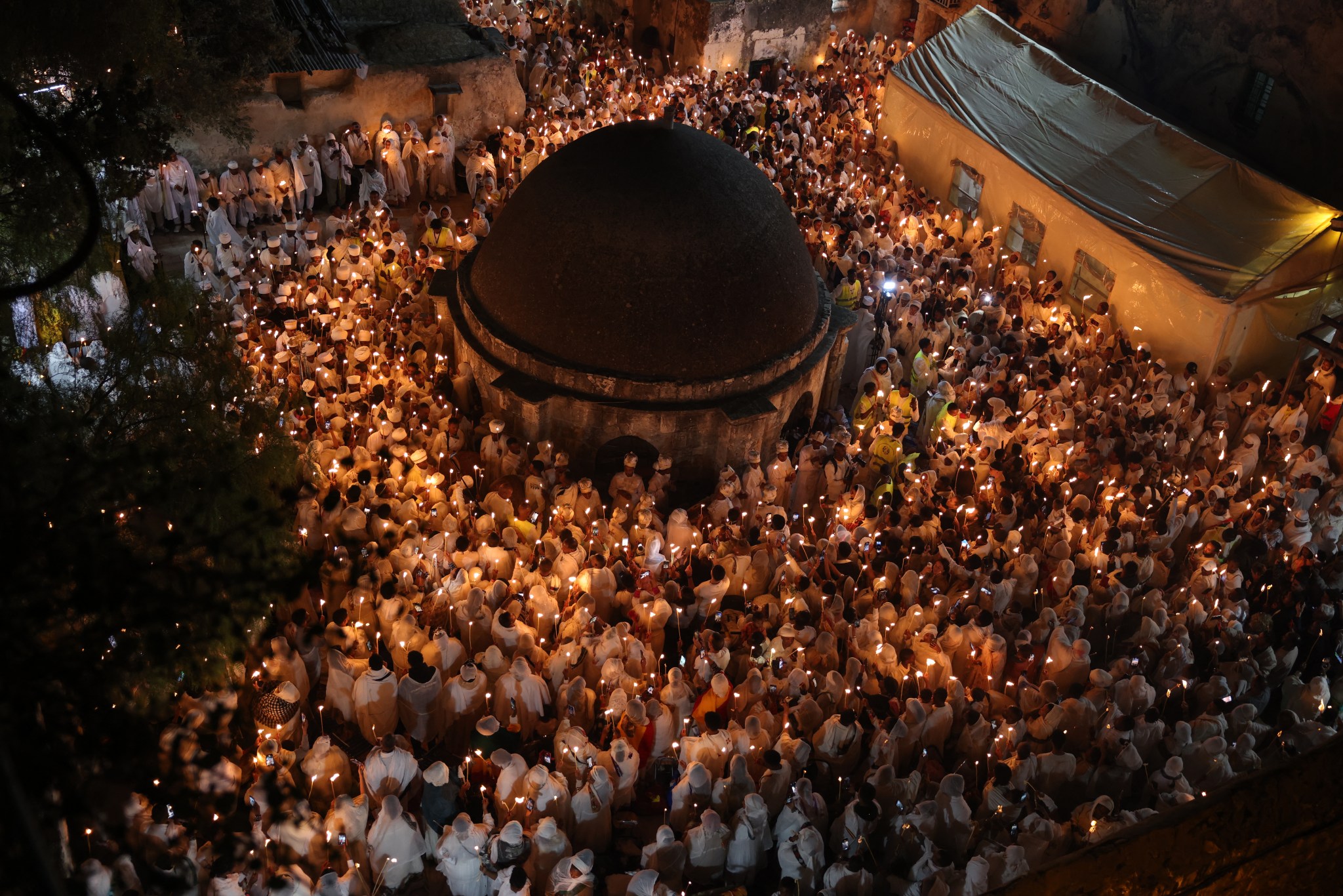 Ethiopian Orthodox Christian pilgrims hold candles during the ceremony of the "Holy Fire" at the Deir Al-Sultan Monastery on the roof of the Holy Sepulchre Church in Jerusalem's Old City on the eve of Orthodox Easter, which this year aligns with the Western church calendar. (Photo by AHMAD GHARABLI/AFP via Getty Images)