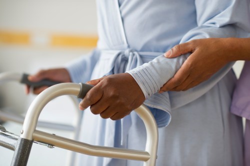 Nurse helping woman use walker in hospital hallway