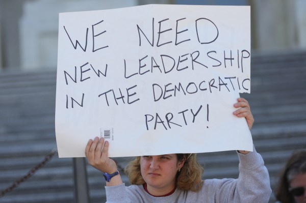 A demonstrator holds a sign during a sit-in protest against a Republican budget plan on the House steps of the U.S. Capitol in Washington, D.C., on April 27, 2025. (Photo by Bryan Dozier / Middle East Images / Middle East Images via AFP) (Photo by BRYAN DOZIER/Middle East Images/AFP via Getty Images)