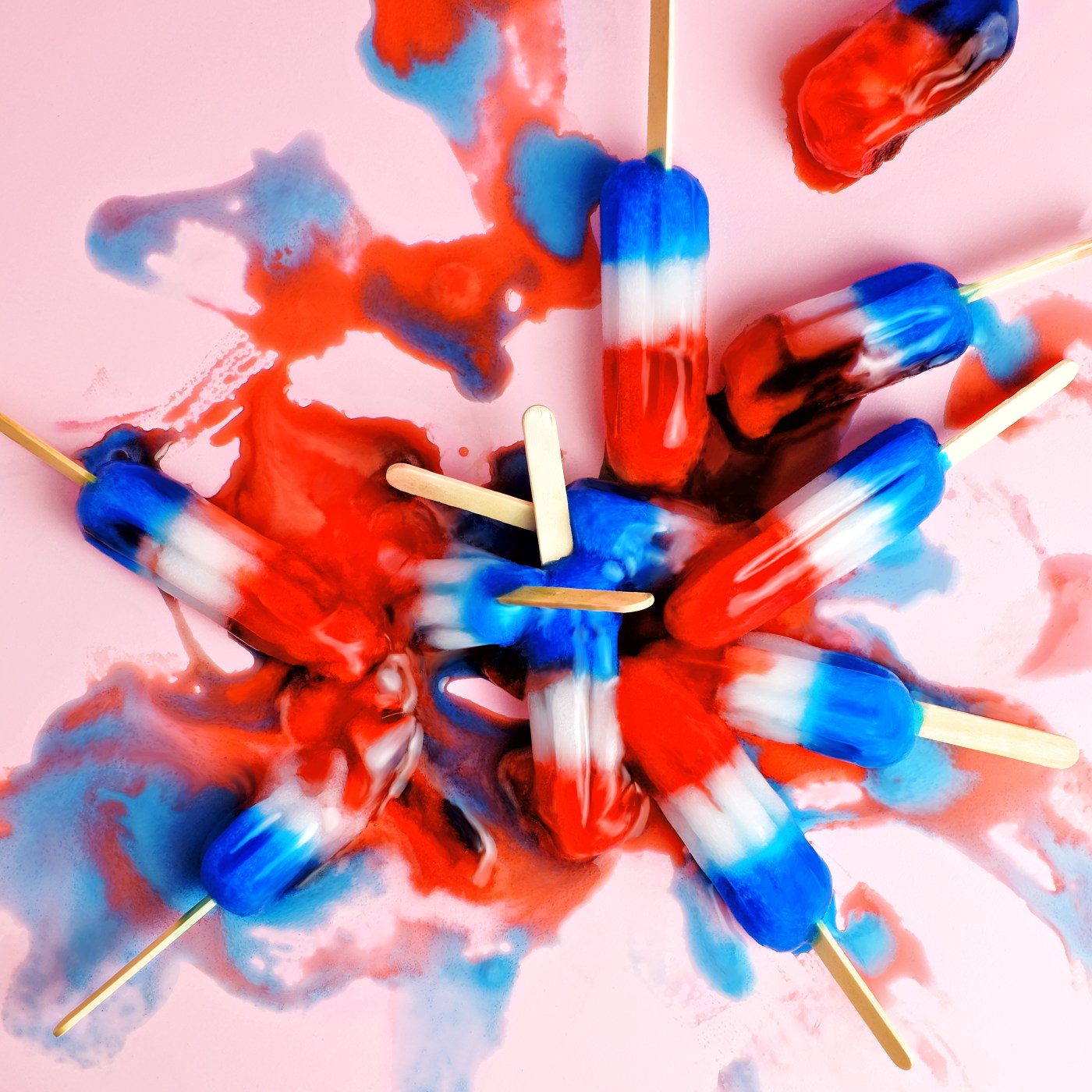 A pile of red, white, and blue ice pops in a melted puddle.