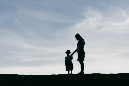 Young mother holding her daughter in the sunset