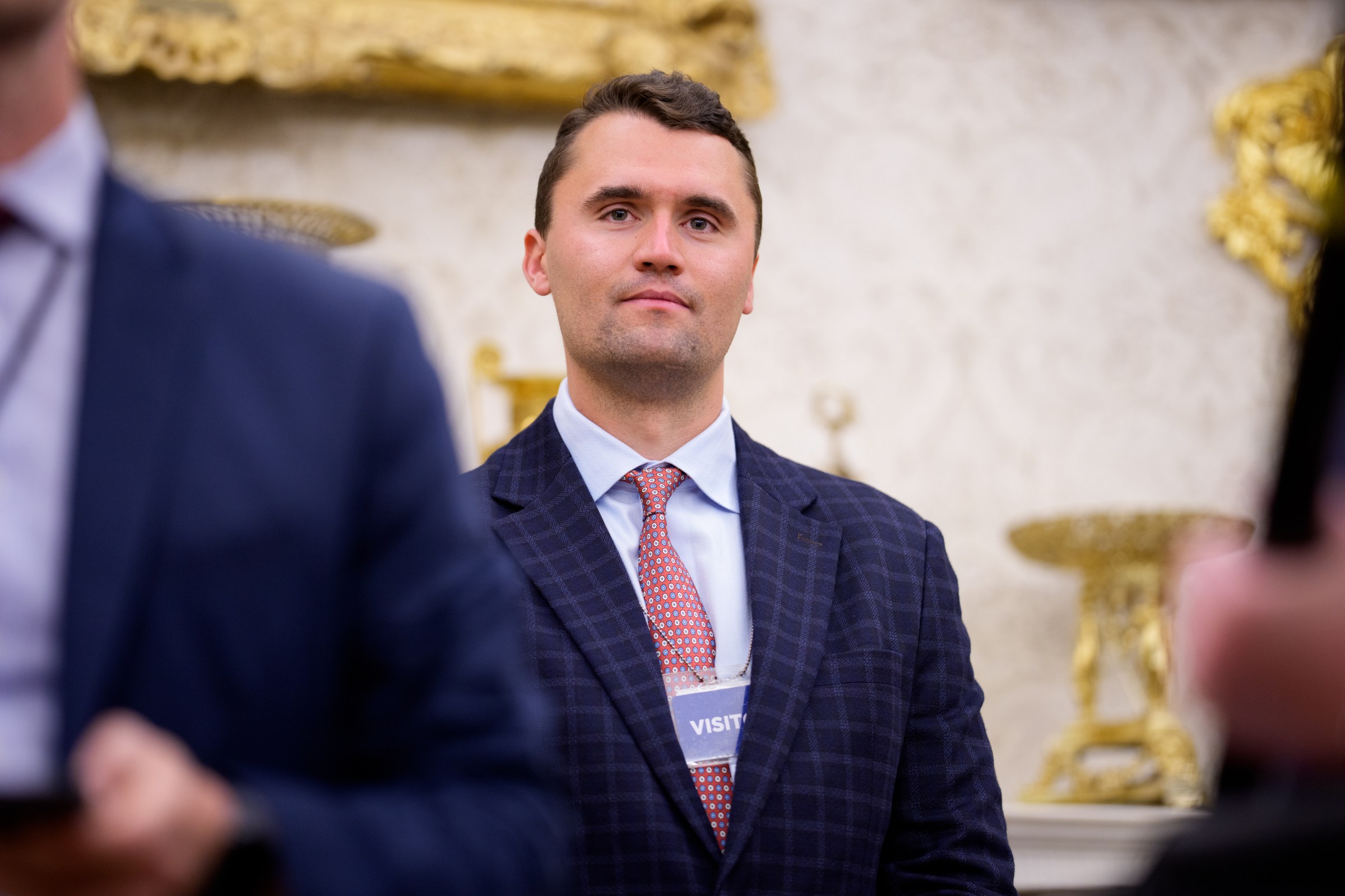 Turning Point USA co-founder Charlie Kirk stands in the back of the room as President Donald Trump speaks during a swearing-in ceremony in the Oval Office of the White House on May 28, 2025. (Photo by Andrew Harnik/Getty Images)