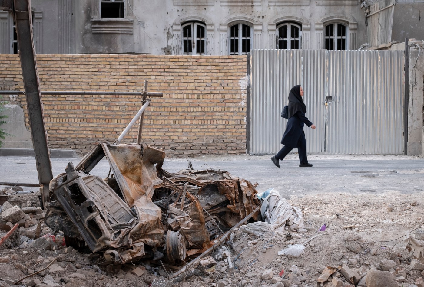 An Iranian woman walks past rubble from Israeli attacks in Tehran, Iran. (Photo by Morteza Nikoubazl/NurPhoto via Getty Images)