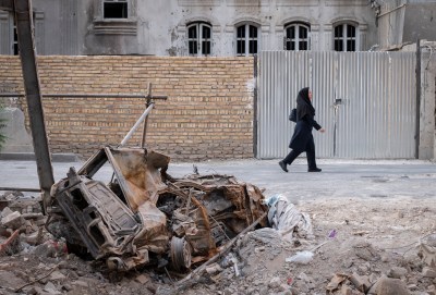 An Iranian woman walks past rubble from Israeli attacks in Tehran, Iran. (Photo by Morteza Nikoubazl/NurPhoto via Getty Images)