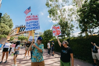 Protesters hold signs outside Walt Disney Studios in Burbank, California on Sept. 19, 2025. (Photo by David Pashaee / Middle East Images/AFP/Getty Images)