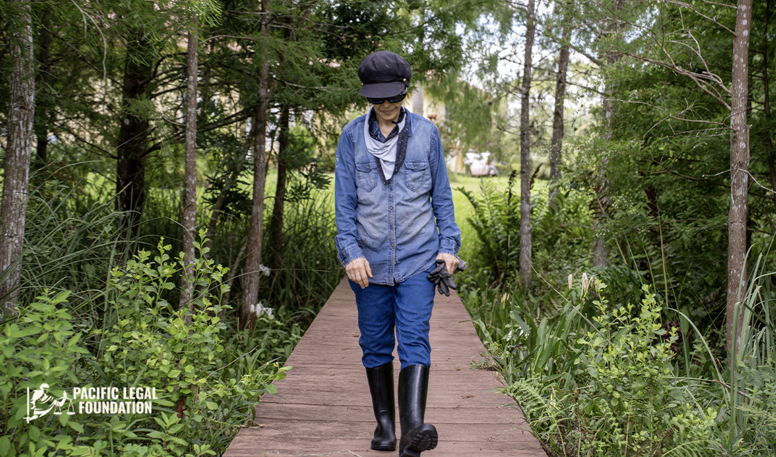 Dispatch Energy Week 3 image A woman wearing a hat and boots walking on a wooden path