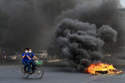 A man and woman riding a bicycle on fire