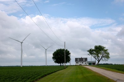 Windmills in a field with a house and trees in the background