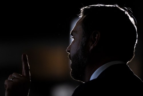 A man in a suit holding up his hand