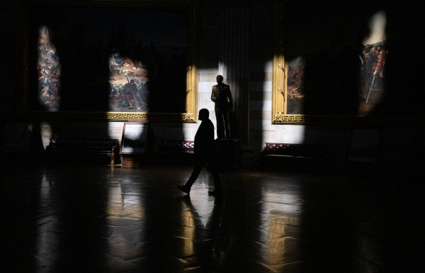 A silhouette of a man walking in a room with a statue