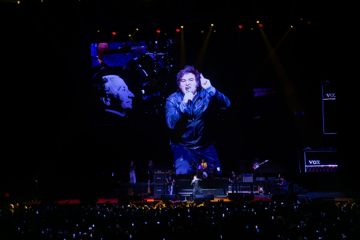 A man on a stage with a large screen