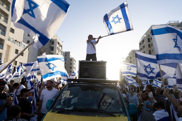 A man standing on top of a car with a flag on top