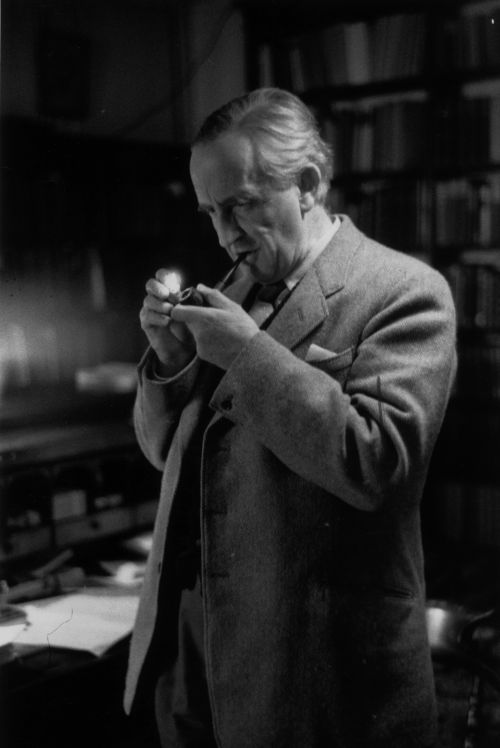 A man in a suit holding a pipe