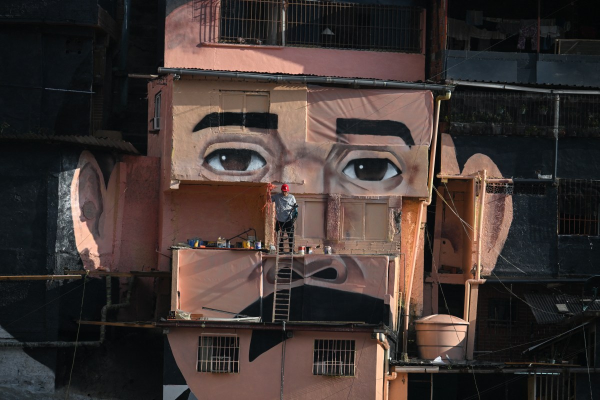 A man works in front of a giant mural of Venezuelan doctor José Gregorio Hernández, also known as “the doctor of the poor,” painted across houses in the El Saman de Bolívar community, in the Petare neighborhood of Caracas, on October 17, 2025. Pope Leo XIV is set to canonize Venezuela’s first saints, Gregorio Hernandez and Sister Maria del Carmen Rendiles, during a ceremony in St. Peter’s Square on Sunday. (Photo by FEDERICO PARRA/AFP via Getty Images)
