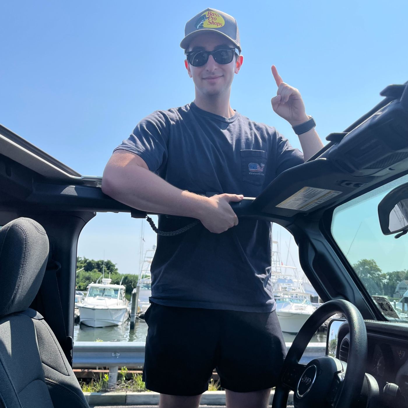 A man in a hat and sunglasses standing in a car