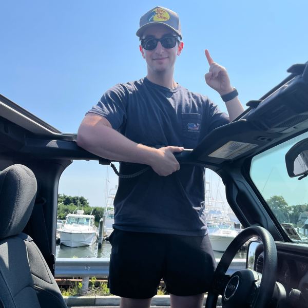 A man in a hat and sunglasses standing in a car