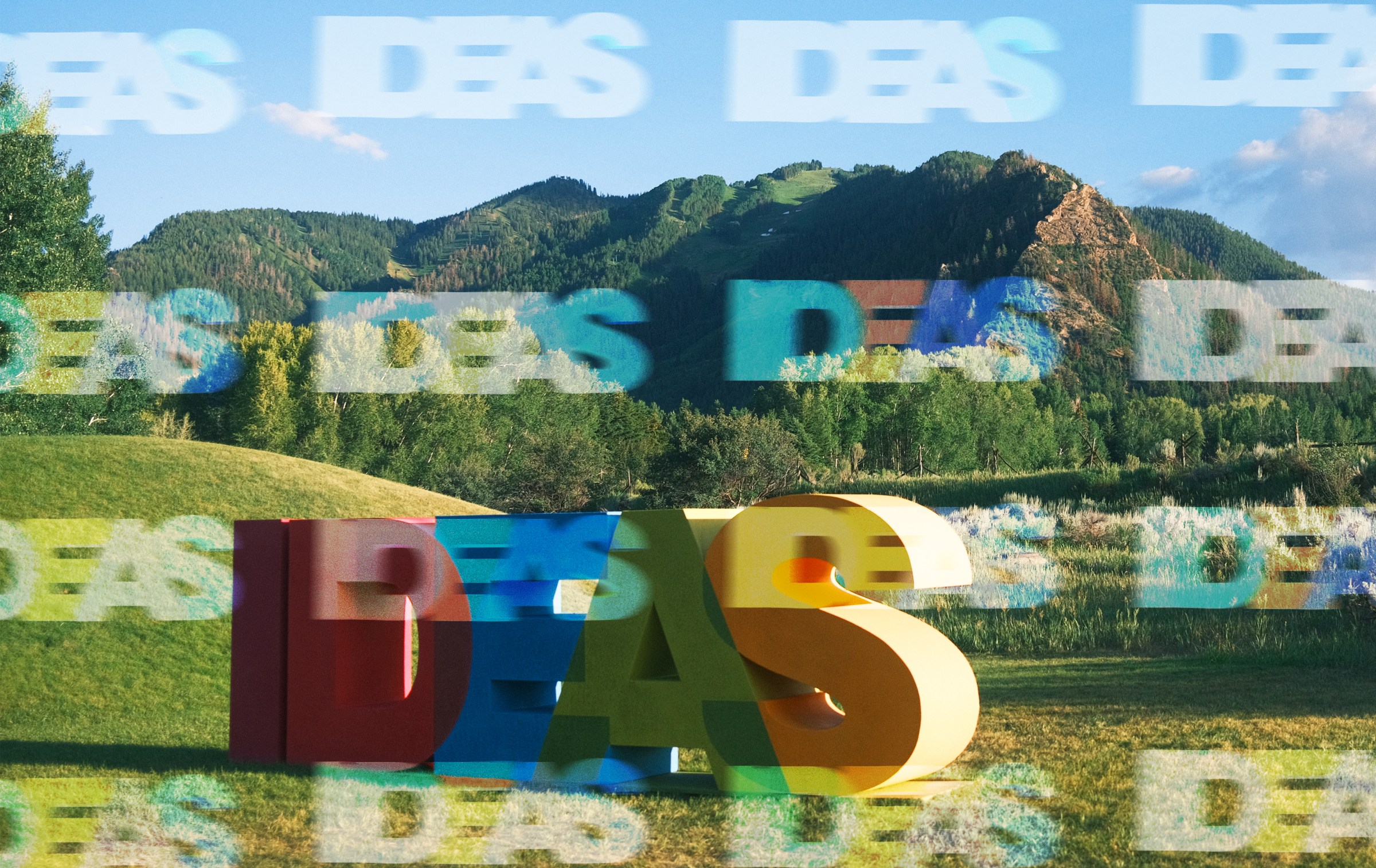 A large colorful letters in a field with mountains in the background