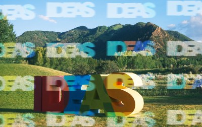 A large colorful letters in a field with mountains in the background