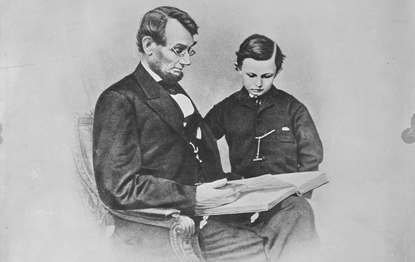 A man and boy sitting in a chair reading a book