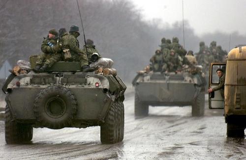 A Russian army convoy passes by a Chechen refugee in December 1999, on its way to cross the Chechen-Ingush border. (Photo by ALEXANDER NEMENOV/AFP via Getty Images)