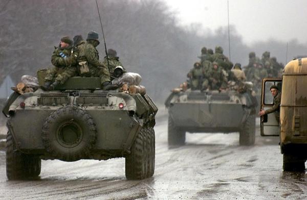 A Russian army convoy passes by a Chechen refugee in December 1999, on its way to cross the Chechen-Ingush border. (Photo by ALEXANDER NEMENOV/AFP via Getty Images)