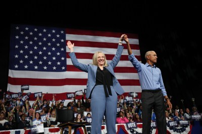 A man and woman holding hands up in front of a flag